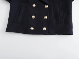 Detailed close-up of navy blue wool coat featuring six golden embossed double-breasted buttons