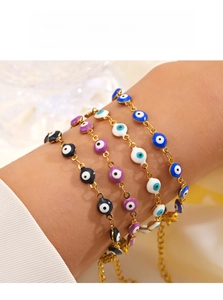 Close-up of four colorful evil eye enamel bracelets with gold chain on a female wrist