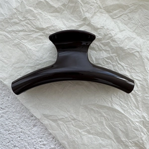 Close-up of curved dark brown glossy PC shark hair claw clip for thick hair styling