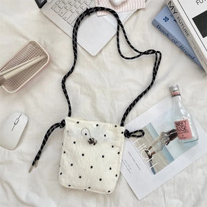Detail of floral crossbody canvas bag with woven rope strap and drawstring on white fabric