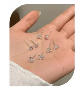 Macro detail of square cut cubic zirconia earrings with silver studs on palm