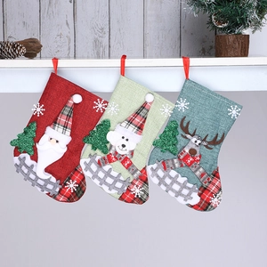 Three linen Christmas stockings with Santa, Snowman, and Reindeer hanging on a shelf