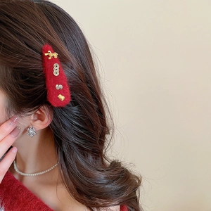 Detail of red plush hair clip with golden bow and bear charms on a female model's side hair