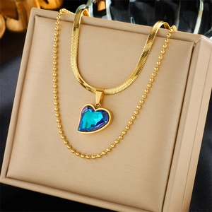 Detail shot of heart-shaped blue gradient pendant on gold snake and bead chains