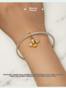 Close-up of s925 silver bee charm with amber crystal on a mesh bracelet worn on wrist
