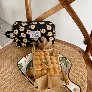 Détail d'une trousse à maquillage en velours côtelé fleuri avec écusson Wild Flower