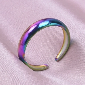 Macro shot of an adjustable rainbow finish stainless steel ring on pink silk fabric
