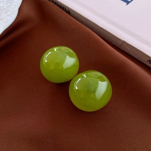 Detail view of round green resin earrings on brown velvet with vintage props