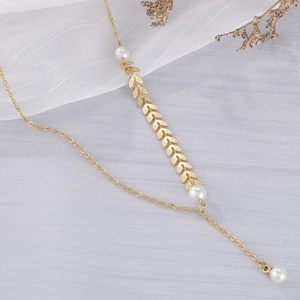 Elegant gold leaf Y-necklace with white pearls on a soft grey mesh background
