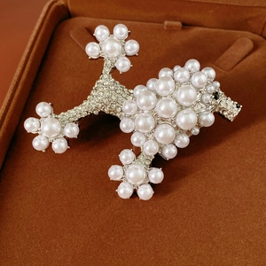 Detailed close-up of a poodle-shaped brooch featuring white pearls and sparkling rhinestones