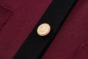 Detailed macro view of gold crest button on burgundy and black knit cardigan fabric
