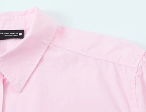 Detailed view of pink poplin shirt neckline with XS size label and premium stitching