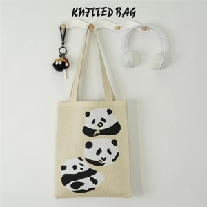 Detail of a beige knitted panda tote bag with earphone and keychain accessories