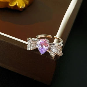 Macro shot of silver bow ring featuring a pear-cut pink zircon and pavé crystal wings