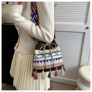Detail of bohemian woven bucket bag with fringe tassels and colorful ethnic strap
