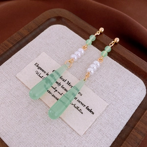 Detailed close-up of green beaded earrings with white pearls and gold metal accents