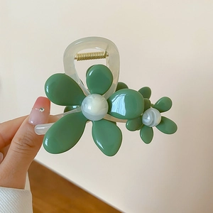 Dettaglio di un fermaglio per capelli a fiore in acrilico verde con finitura trasparente