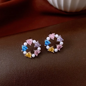 Detailed macro view of colorful heart-shaped zircons and white pearls on circular earrings