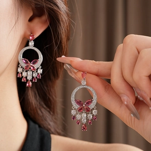 Detail of silver butterfly drop earrings with sparkling red and pink zircon tassels