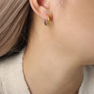 Minimalist geometric two-tone hammered gold and silver hoop earrings on a model