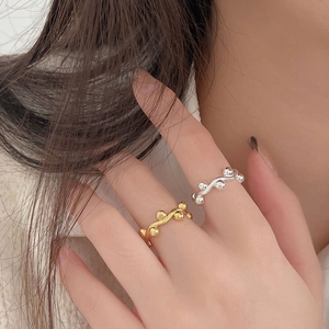 Macro detail of wave vine design rings with metallic beads in gold and silver finish