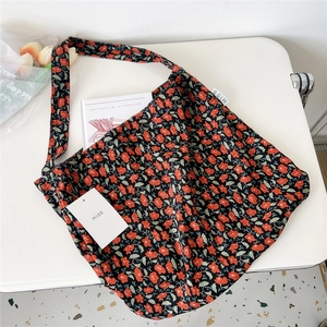 Close-up of black corduroy tote bag with red floral pattern and brand label