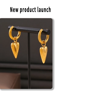 Detailed view of polished heart charms on 18k gold plated stainless steel hoop earrings