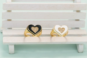 Detail of gold-plated heart rings with black and white enamel and zircon stones