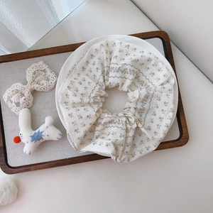 Detailed macro view of white floral cotton scrunchie with blue prints on ceramic tray