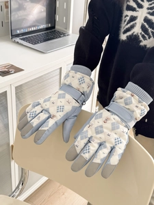 Detail of blue quilted ski gloves featuring bear pattern and adjustable wrist straps