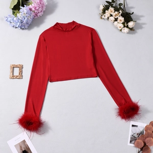 Detail of red mock neck cropped top featuring faux feather cuffs and elastic fabric