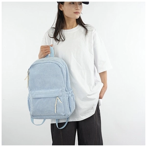 Detailed view of light blue corduroy backpack worn by a model in a minimalist style