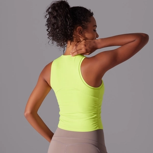 Détail du haut de yoga jaune fluo avec plis latéraux et coupe ajustée pour le fitness