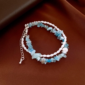 Makro-Detail des doppellagigen Armbands mit blauen Natursteinen und weißen Muschelperlen