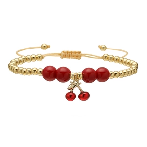 Adjustable gold beaded bracelet featuring a red cherry pendant and woven cord strap