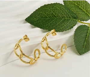 Detail of 18K gold plated hoop earrings with chain texture on a white textured base