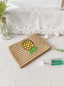 Handmade beige paper straw clutch bag featuring yellow pineapple embroidery pattern