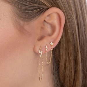 Macro view of gold S925 sterling silver star and lightning earrings with zircon chains