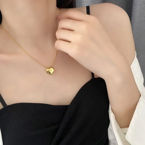 Elegant 3D golden heart pendant necklace on minimalist chain worn by a female model