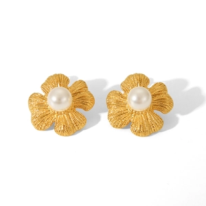 Detailed macro view of 18k gold floral earrings with a white pearl center and matte petals