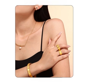 Dettaglio del set bracciale e anello con fiori in rilievo dorati indossati dal modello