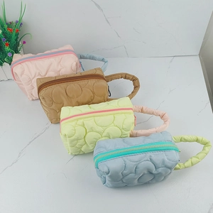 Quilted cosmetic bags in four pastel colors with zip closure and top handles on marble