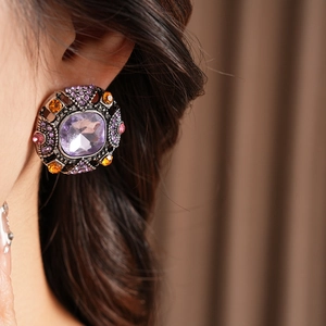 Close-up of vintage round earring with purple rhinestone and antique bronze finish