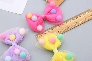 Detail showing colorful mesh bow hair clips with soft pom-poms and sizing ruler measurement