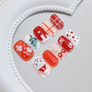 Detail of Christmas press-on nails featuring snowman and snowflake designs on a heart mirror