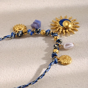 Detail of woven rope bracelet featuring 18K gold sun moon pendants and freshwater pearl