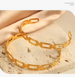 Detailed close-up of 18K gold plated chain-link bangles on elegant silk and stone