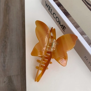 Detailed close-up of a marble texture amber acetate butterfly hair claw clip with engraving