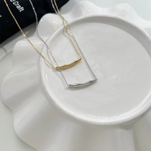 Gros plan de colliers sourire en bambou or et argent sur une assiette en céramique