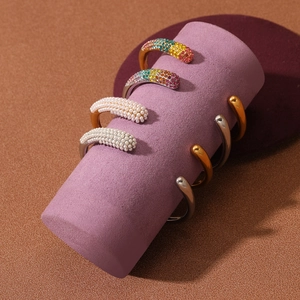 Golden and silver stainless steel bangles with colorful rhinestones and pearls on display